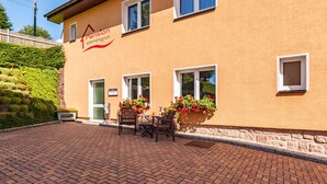 A building with a sign reading "Pension Wernesgrün" and a patio area with a table and chairs. - Pension Wernesgrün (Steinberg)