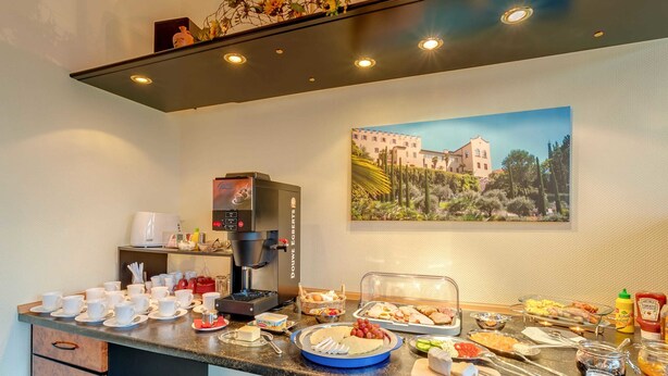 A breakfast buffet setup with coffee machines, a variety of food items, and a scenic wall painting. - Pension Wernesgrün (Steinberg)