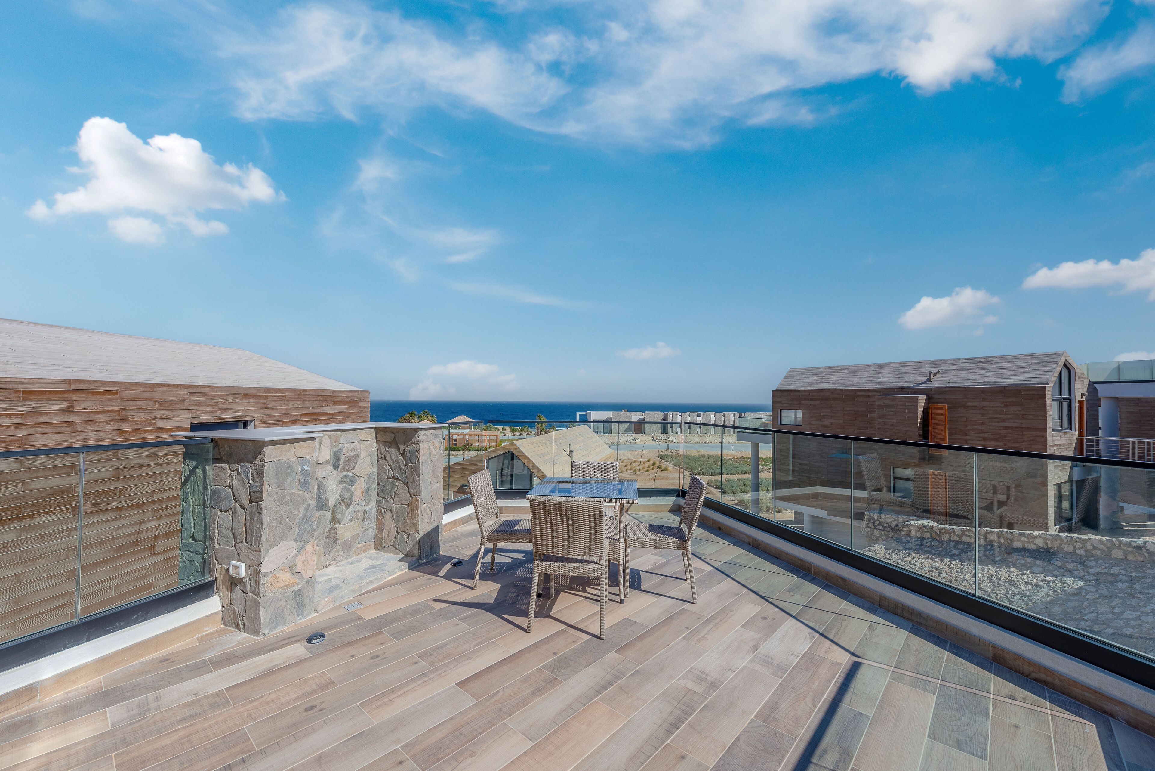Eine Dachterrasse mit Glasgeländer, einer Steinmauer und einem Holzboden.