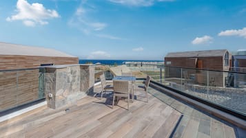 Eine Dachterrasse mit Glasgeländer, einer Steinmauer und einem Holzboden.