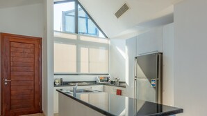 A modern kitchen with a large island, a built-in refrigerator, and a window providing natural light. - VESTA - Soma Bay Residence (Soma Bay)
