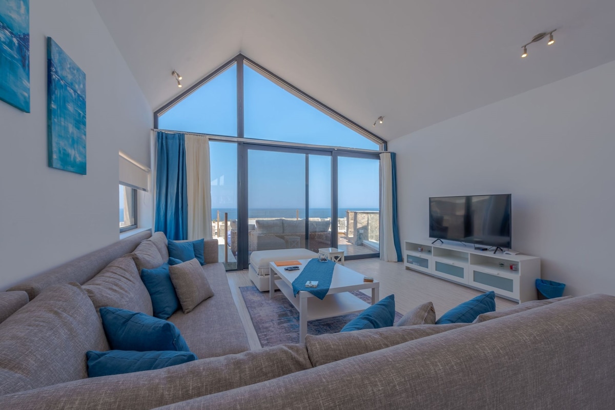 A modern living room with a large window, a sofa, a coffee table, and a TV.