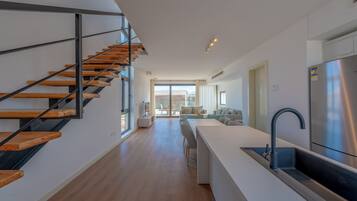 Eine moderne Küche mit einem Edelstahl-Kühlschrank, einer integrierten Spüle und einer Holztreppe.