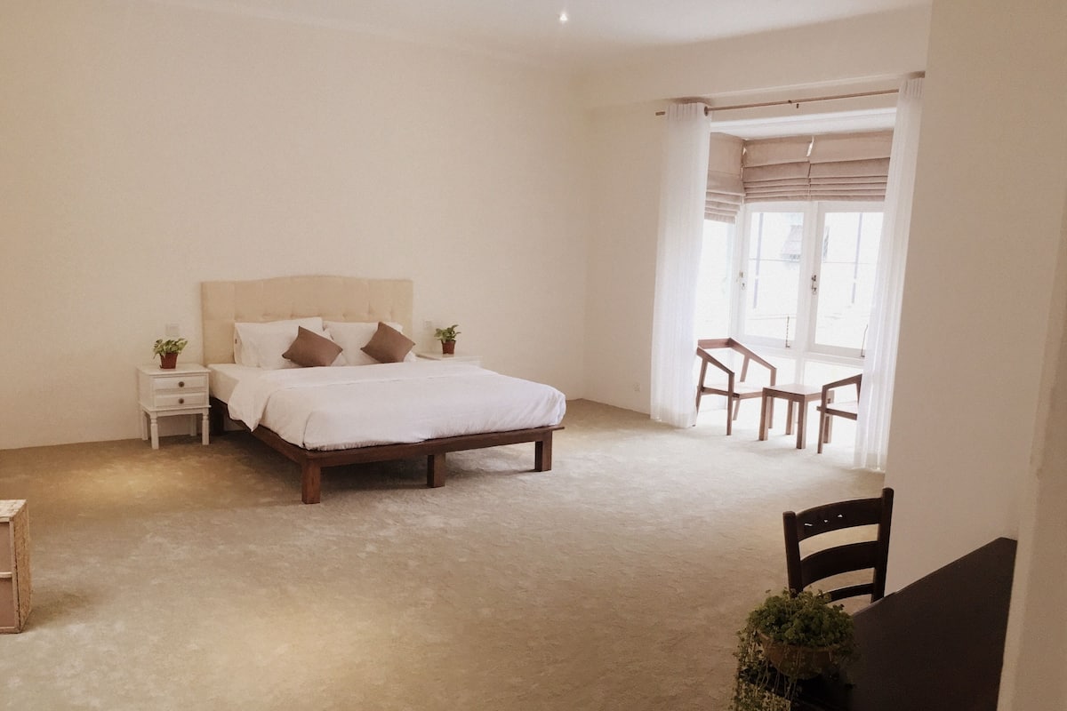 A bedroom with a bed, bedside tables, a chair, and a table.