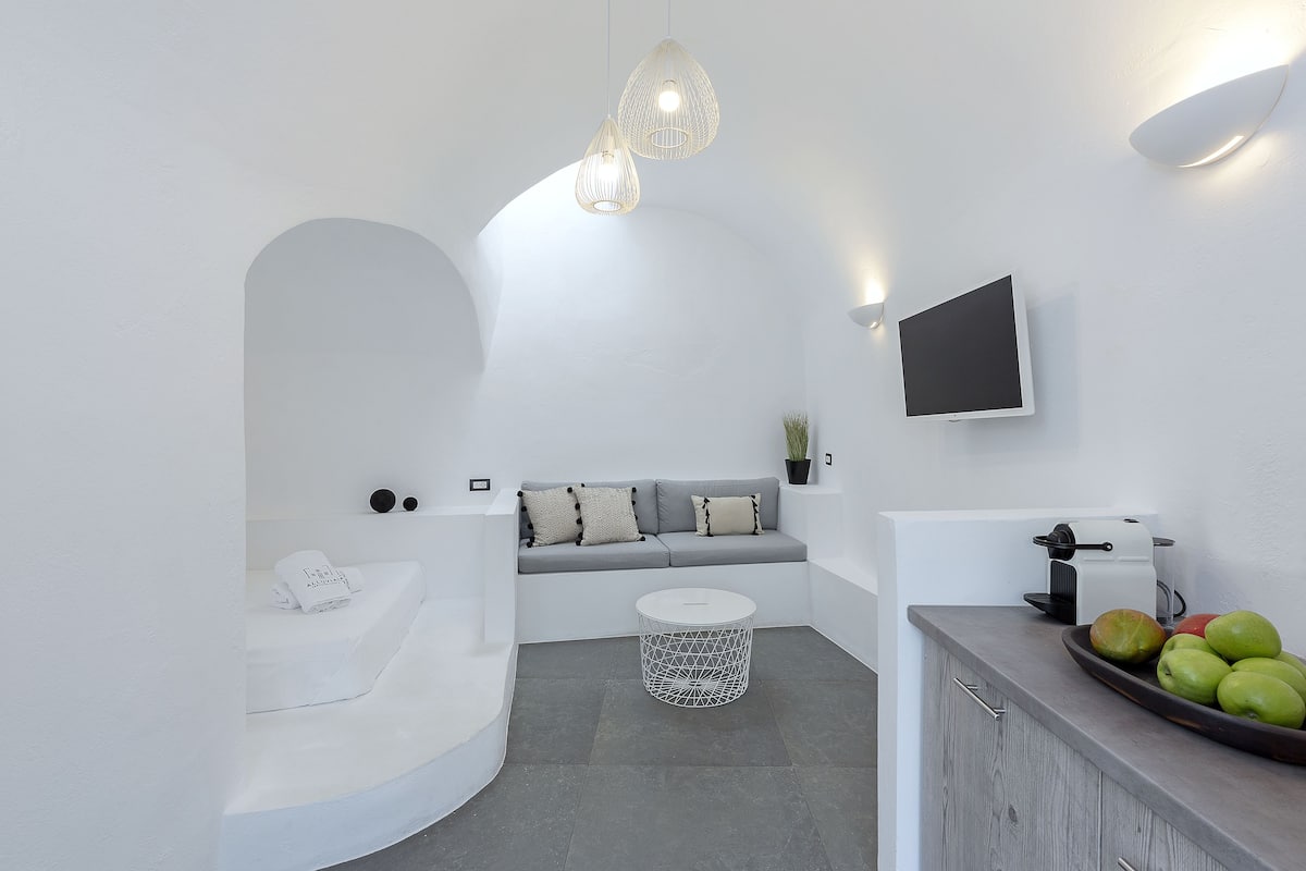 A modern, minimalist bathroom with a white bathtub, a round white sink, and a countertop with fruits.