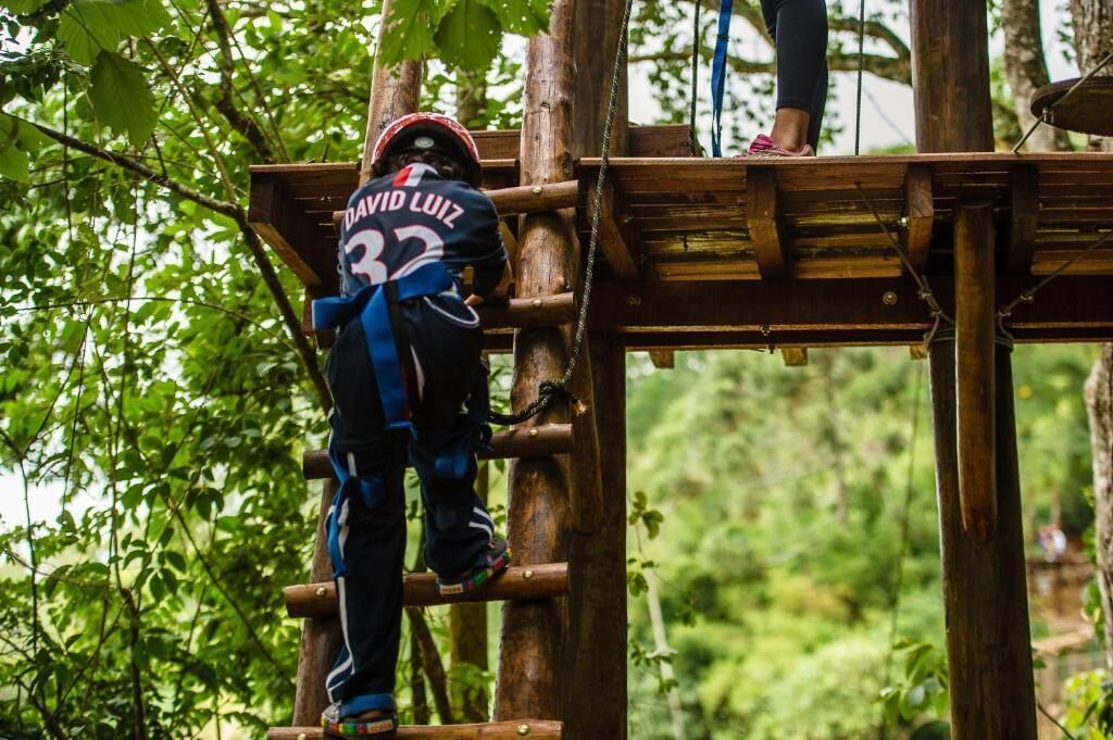 Eine Person klettert auf einer Holzkonstruktion in einem bewaldeten Gebiet.