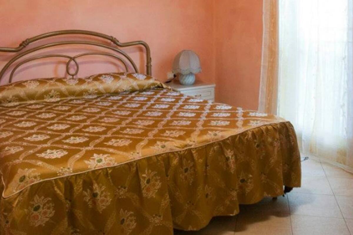 A bedroom with a bed, a nightstand, and a window with curtains.