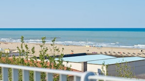 Vista da praia com céu claro, areia dourada e alguns guarda-sóis.