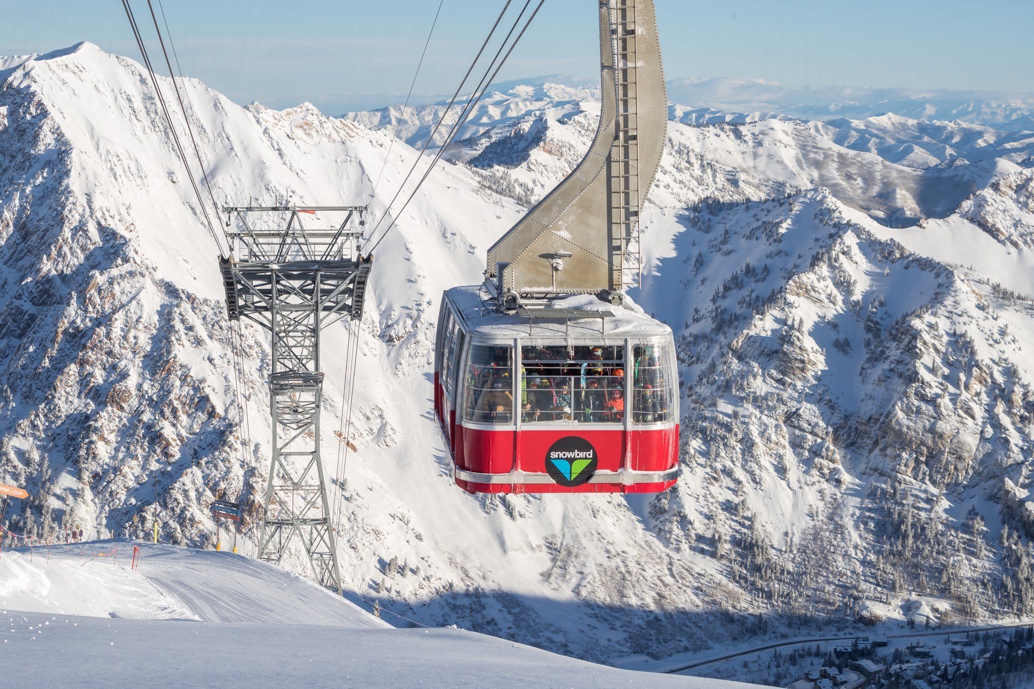 A cable car ascending a snowy mountain with a clear view of the surrounding landscape.