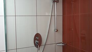 A shower with a handheld showerhead and a wall-mounted control panel.