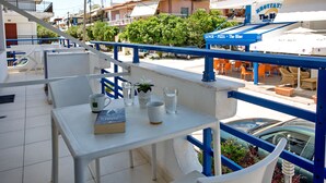 A balcony with a table, chairs, a book, a mug, and a glass of water. - The Blue Apartments and Beach (Pangaio)