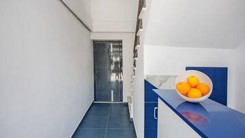 A modern hallway with a blue counter and a bowl of oranges.