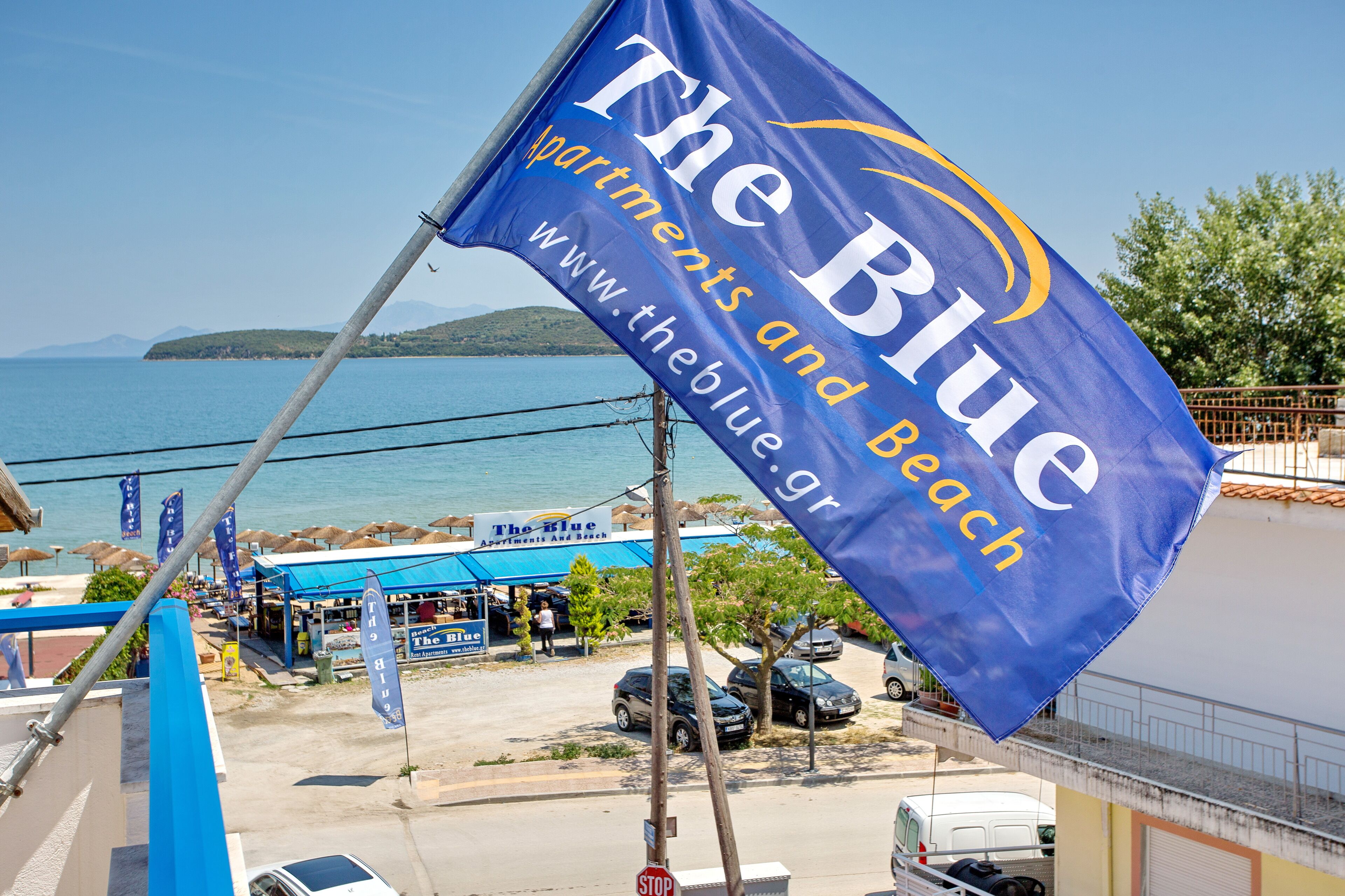 Et flag med teksten "The Blue Apartments and Beach" og en hjemmesideadresse.