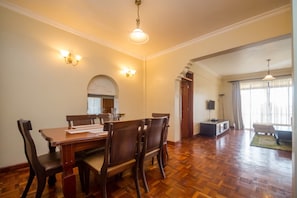 Un comedor con mesa y sillas de madera, una lámpara de araña y apliques en la pared.