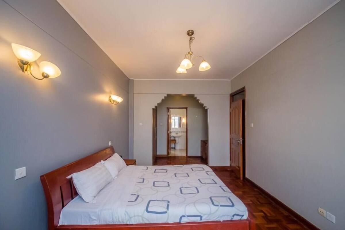 A bedroom with a wooden bed, a hallway, and a staircase leading to a bathroom.