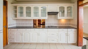 A kitchen with white cabinets, a black countertop, and a gas stove. - KenGen Furnished and Serviced Apartments (Nairobi)