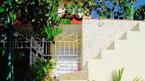 A stone staircase leading to a building entrance, surrounded by potted plants and a metal gate. - Villa Cristal Holguin (Holguín)