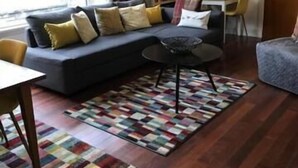 A cozy living room with a sofa, a coffee table, and a bookshelf. - Millview Bed & Breakfast (Ullapool)