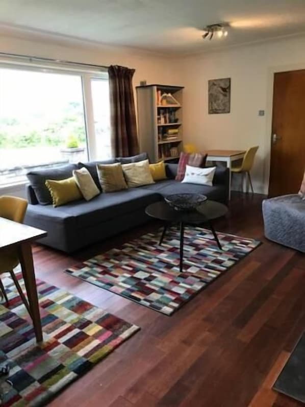 A cozy living room with a sofa, a coffee table, and a bookshelf.