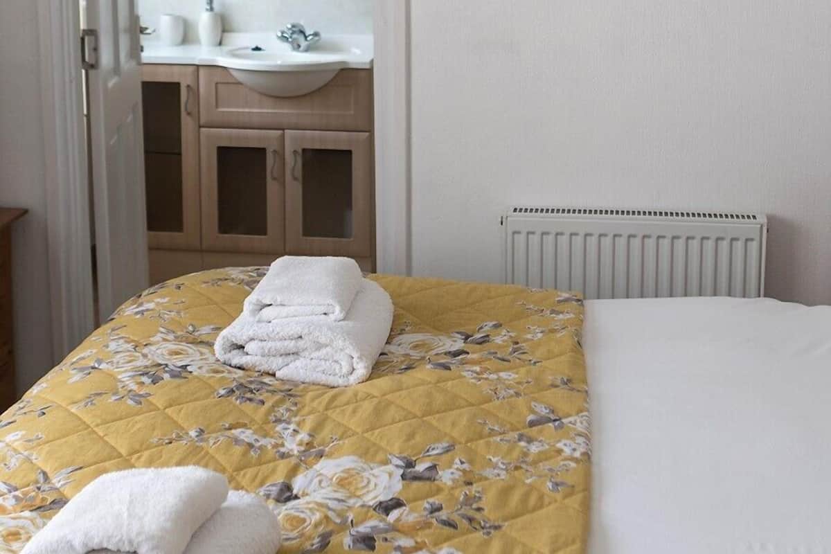 Ein Hotelzimmer mit einem Bett, einem Badezimmer mit Waschbecken und Spiegel sowie einem gerahmten Bild an der Wand.