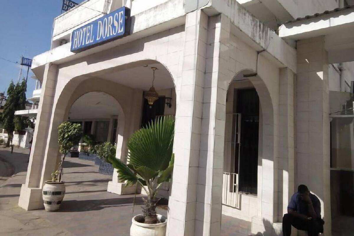 Entrada de hotel con un letrero que dice 'HOTEL DORSE', un arco de entrada y plantas en macetas.