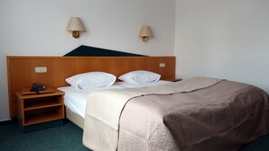 A hotel room with a single bed, a bedside table with a phone, and two wall-mounted lamps. - Hotel Radau (Bad Harzburg)