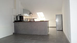 A modern kitchen with a built-in island, a refrigerator, and a skylight. - Hotel Radau (Bad Harzburg)