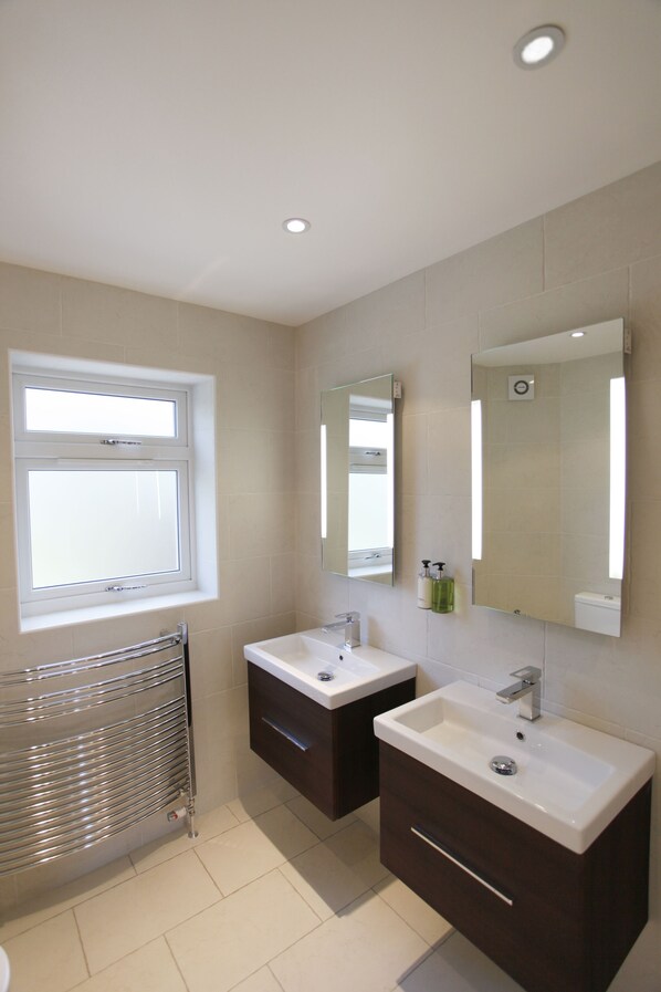 A modern bathroom with two sinks, a window, and a towel rack.