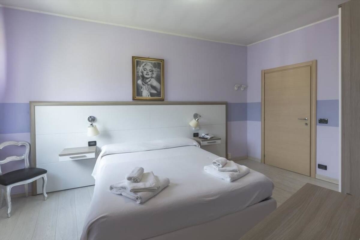Une chambre d’hôtel avec un grand lit, des tables de chevet, une chaise et une porte.