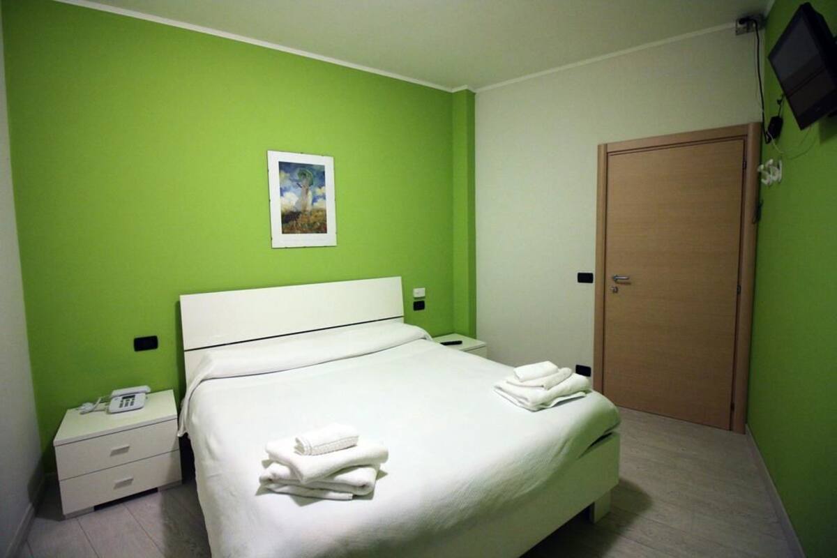 Une chambre d’hôtel avec un lit, une table de chevet, un téléphone et une porte.