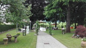 En havegang fører til en pergola med udendørs siddepladser.