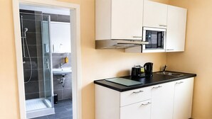 A modern kitchen with white cabinets, a black countertop, and a microwave. - Hotel Select Suites & Aparts (Moenchengladbach)