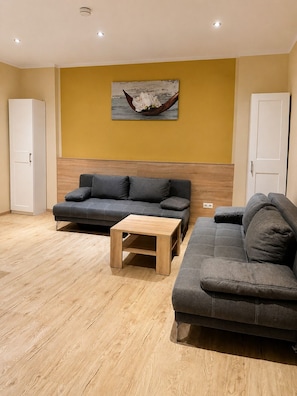 A living room with two sofas, a coffee table, and a wall-mounted picture. - Hotel Select Suites & Aparts (Moenchengladbach)