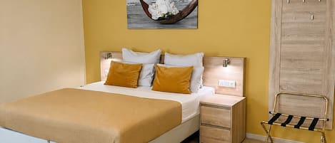 A bedroom with a bed, bedside tables, a hanging light fixture, a wooden wardrobe, and a wall-mounted artwork.