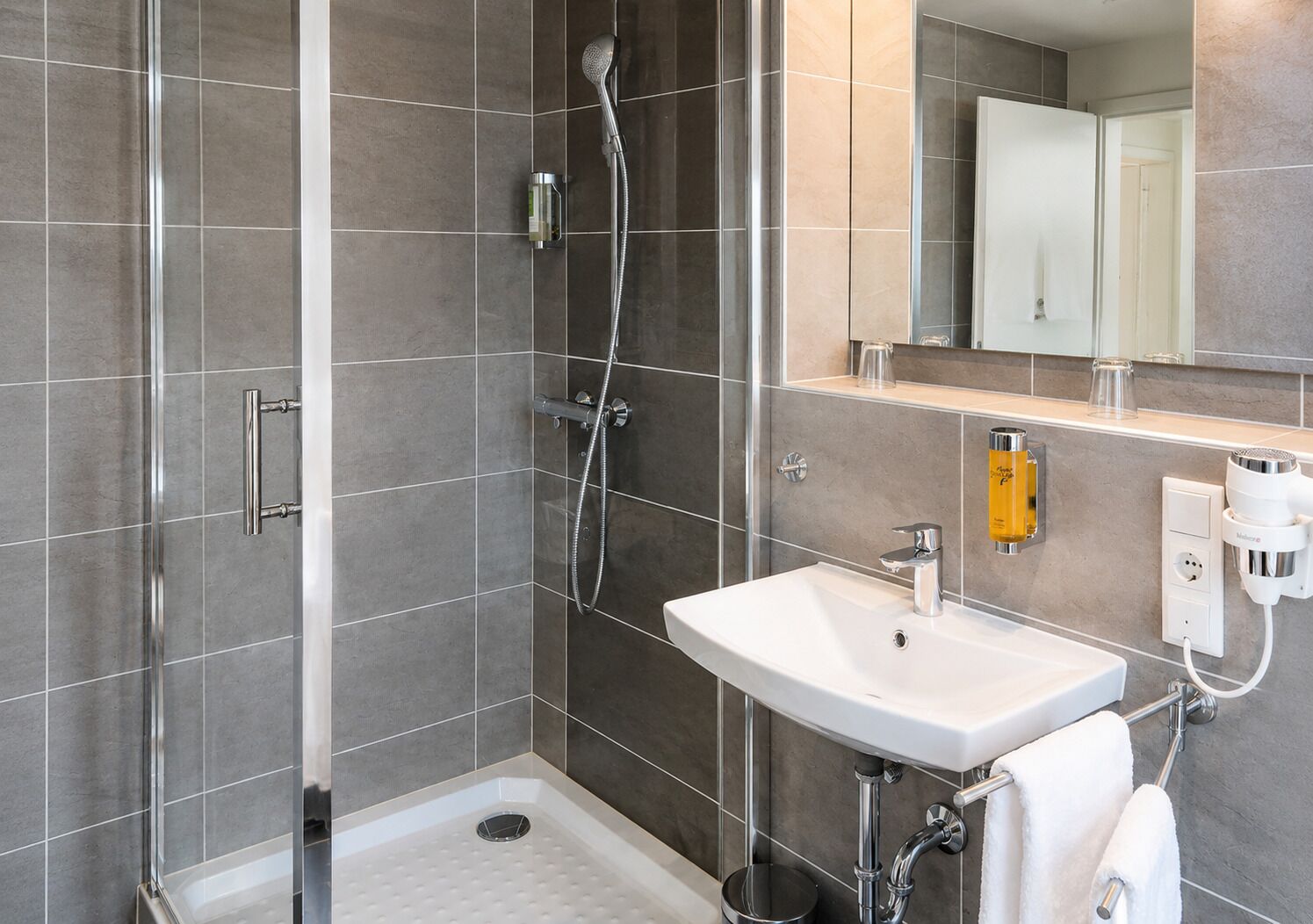 Ein modernes Badezimmer mit Dusche, Waschbecken und Spiegel.