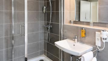 Ein modernes Badezimmer mit Dusche, Waschbecken und Spiegel.