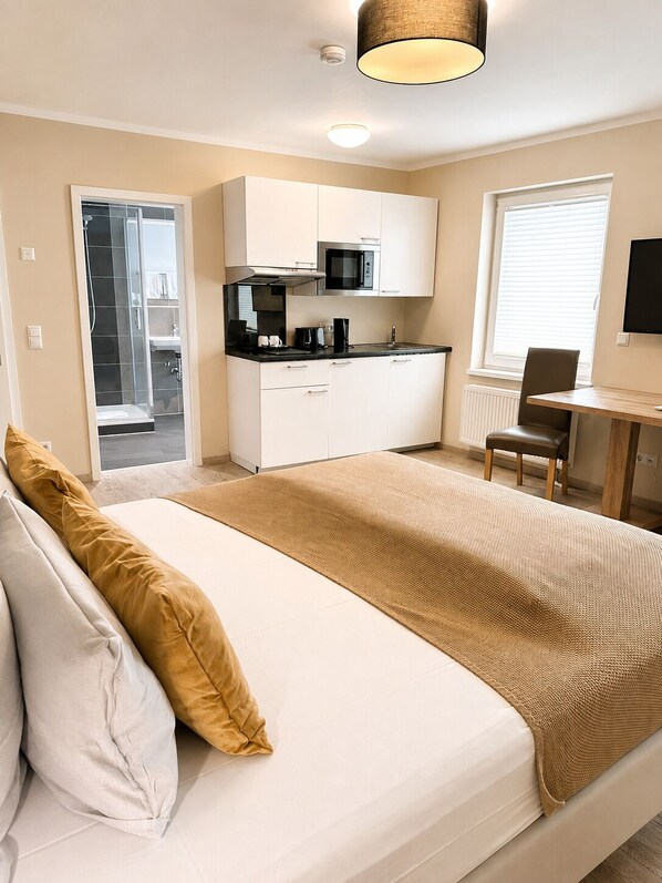 A modern bedroom with a bed, a kitchenette, and a bathroom. - Hotel Select Suites & Aparts (Moenchengladbach)