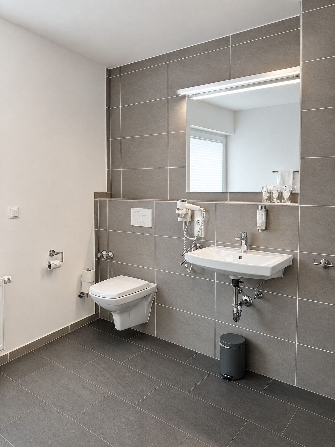 Ein modernes Badezimmer mit Toilette, Waschbecken und Spiegel.