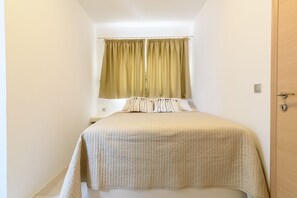 A bedroom with a bed, curtains, and a door. - Villa George Santorini (Santorini)