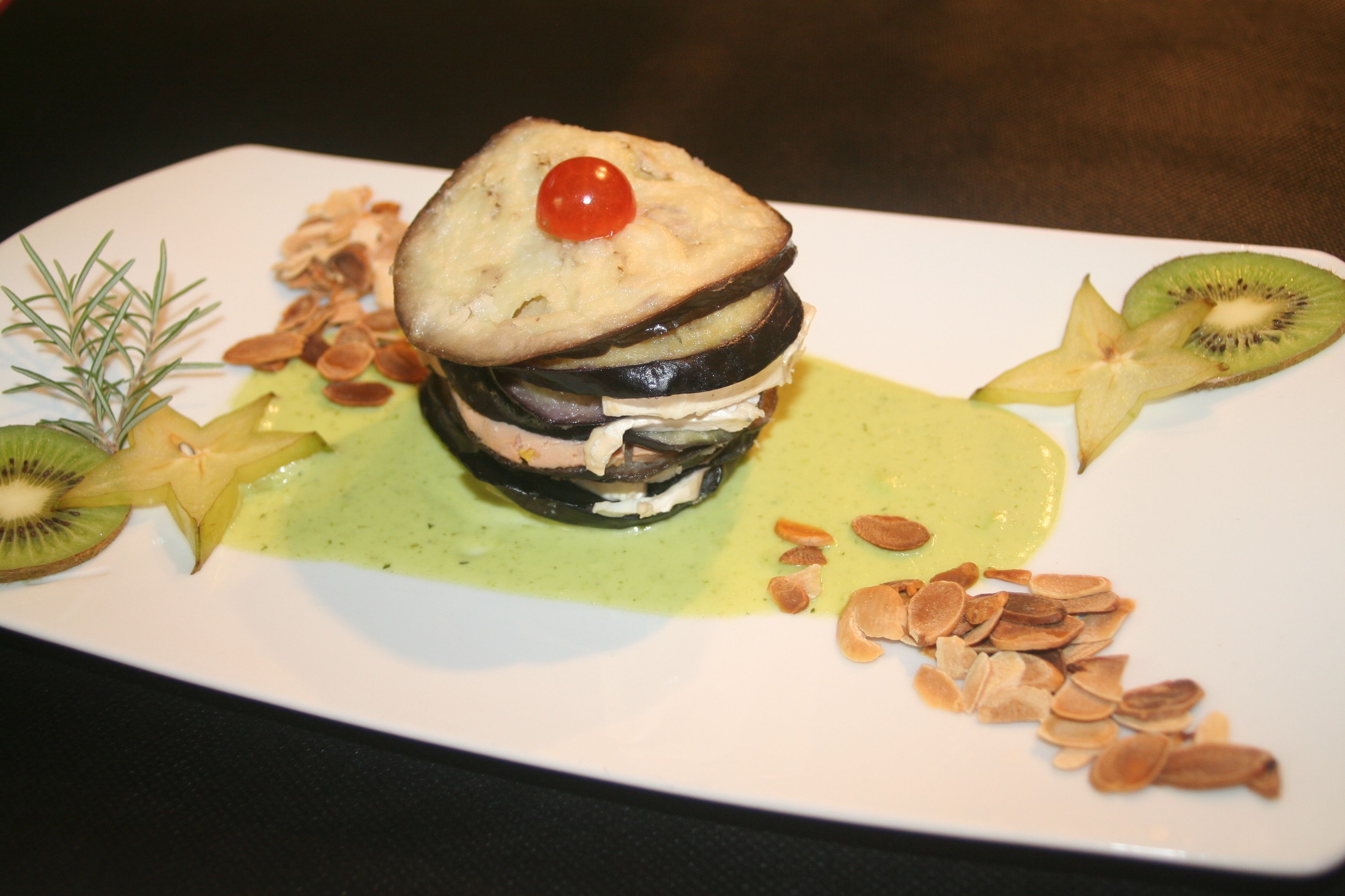 Un postre con capas de bizcocho, fruta y nueces sobre un plato blanco.