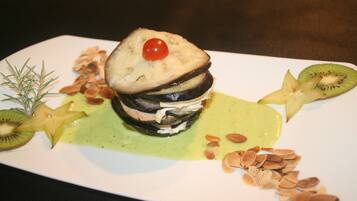 Un postre con capas de bizcocho, fruta y nueces sobre un plato blanco.