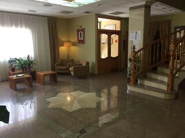 Un vestíbulo con una escalera de madera, un mostrador de recepción y un diseño de piso en forma de estrella.