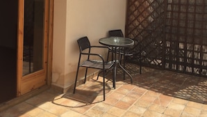 A patio with a wooden ceiling, a glass table, and two chairs. - Hotel Castellote (Castellote)