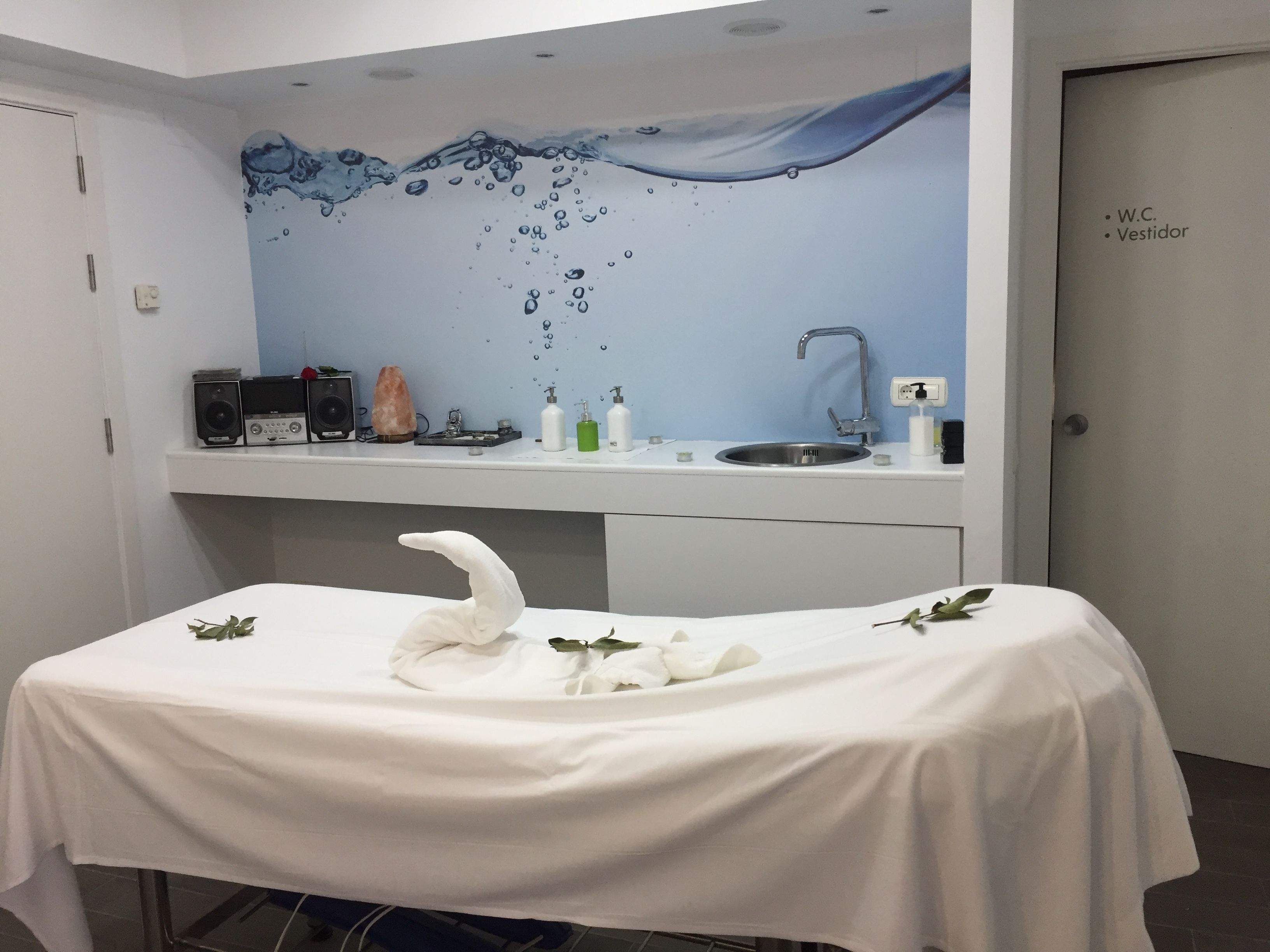 A room with a white table, a sink, and a wall mural.
