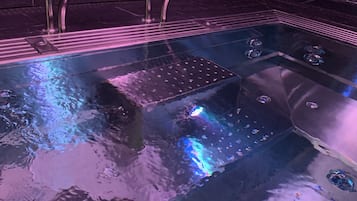 Un jacuzzi con base de vidrio, barandillas de metal y chorros integrados.