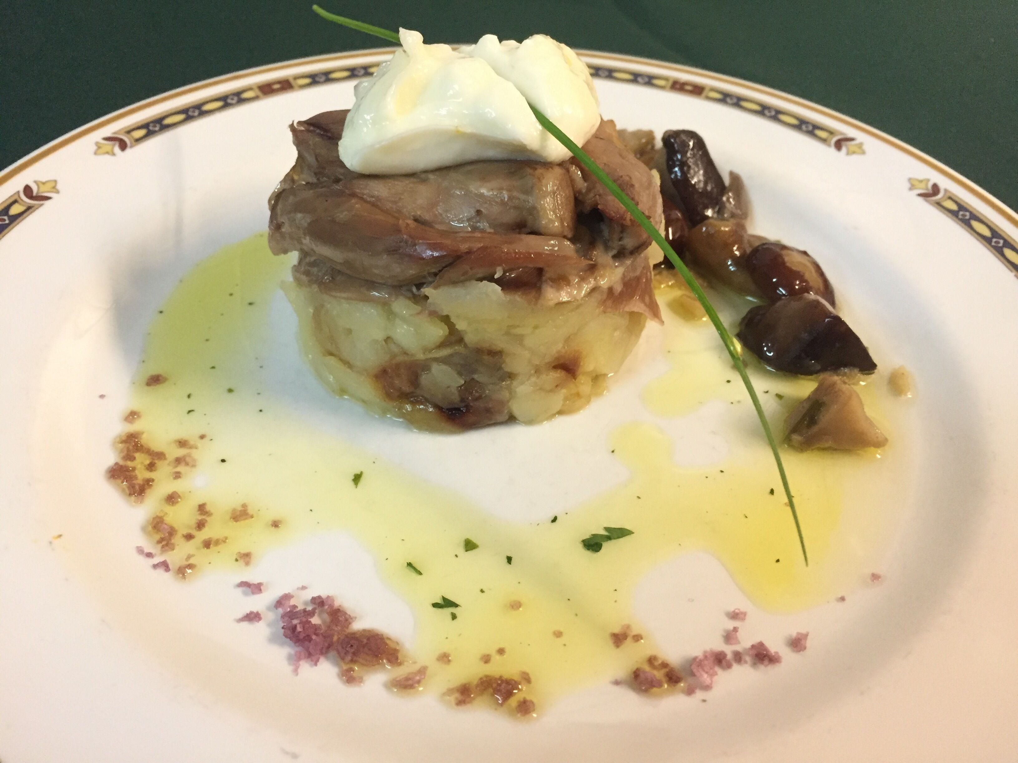 A plate with a layered dish topped with a poached egg and garnished with chives.