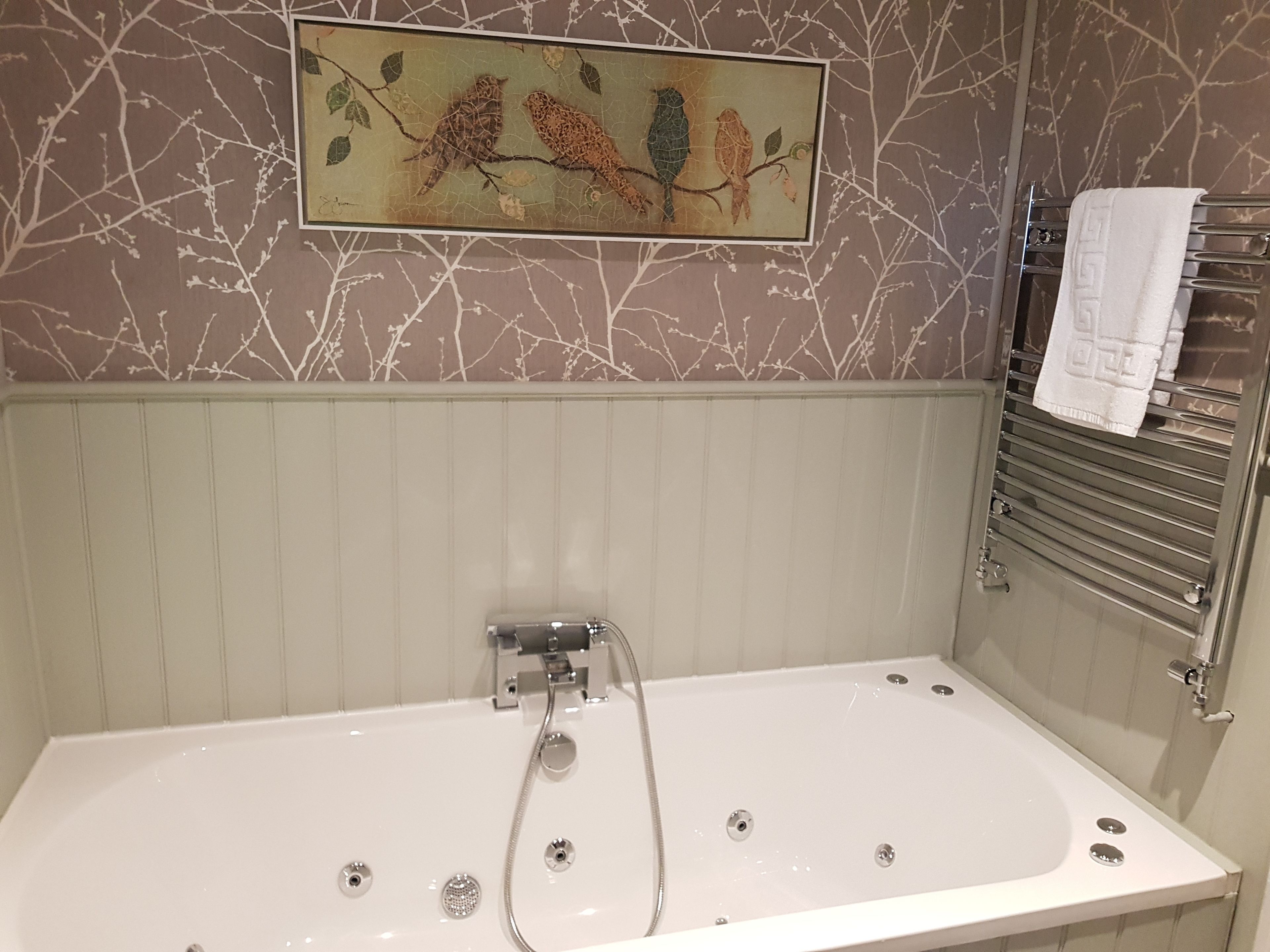 A bathroom with a large bathtub, a shower, and a towel rack with a towel.