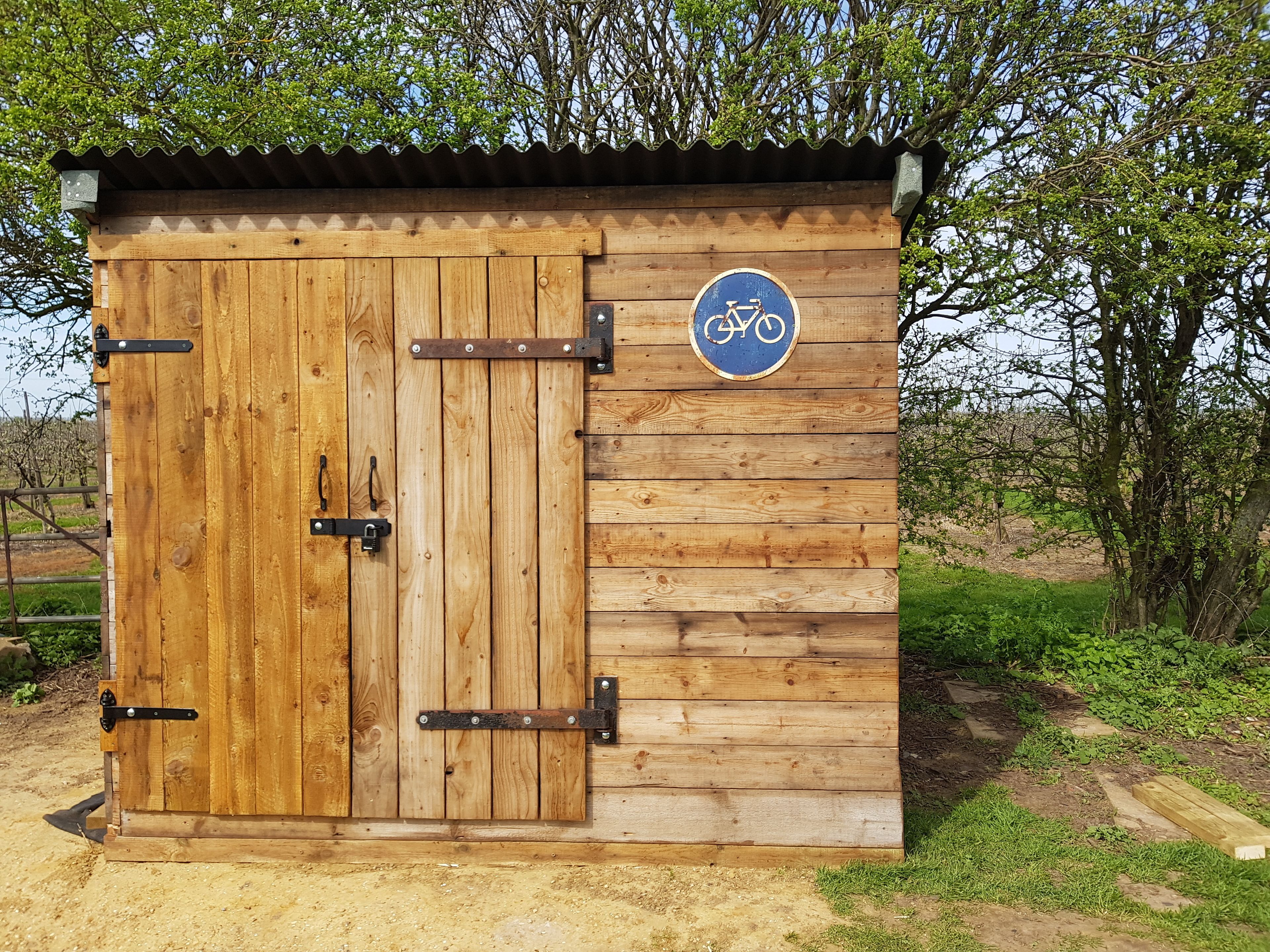 A wooden structure with a bicycle symbol, suggesting it is a bike storage or shelter.