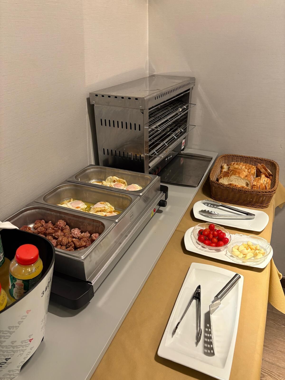 A breakfast buffet with various food options including eggs, sausages, toast, and fruits.