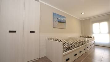 A bedroom with a bed, wardrobe, and a painting of a boat on the wall.